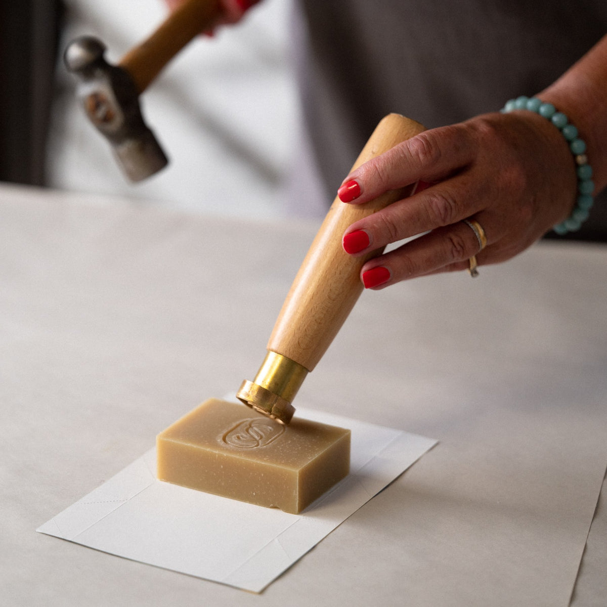 A cold-process Soapsmith soap bar being stamped by hand