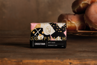 The complete Soapsmith x Crosstown Dirty Sugar soap pack on a wooden table with doughnuts in the background.
