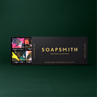 Soapsmith mini soap gift box with the black lid slid open to reveal the wrapped soaps on a green background.